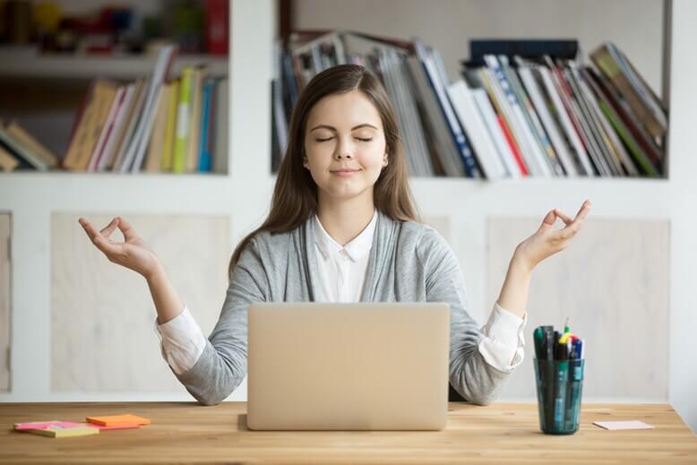 Executiva meditando em frente ao computador para alcançar o estado de mindfulness