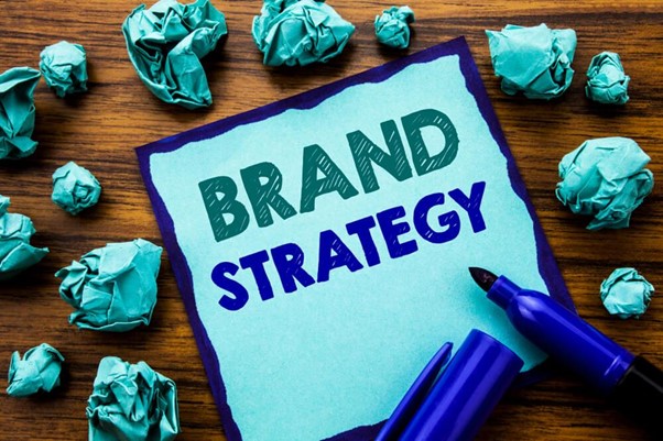 Vários papéis amassados ao redor de uma cartulina com a frase "Brand Strategy"