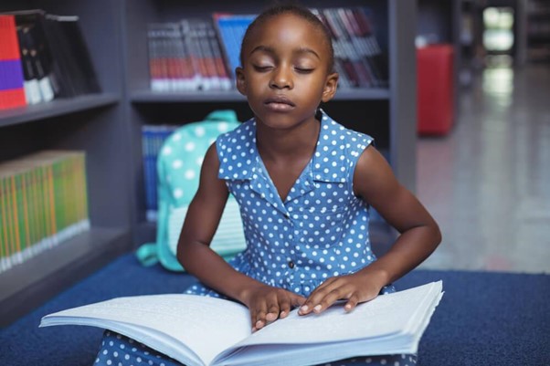 Uma criança lendo um livro em braille, um exemplo de inclusão na educação infantil