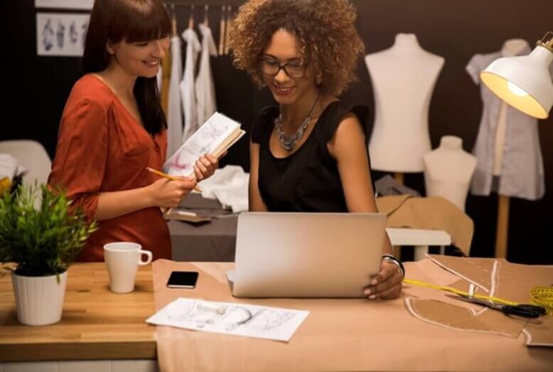 Mulher com características de uma empreendedora fazendo negócios através do notebook em sua loja