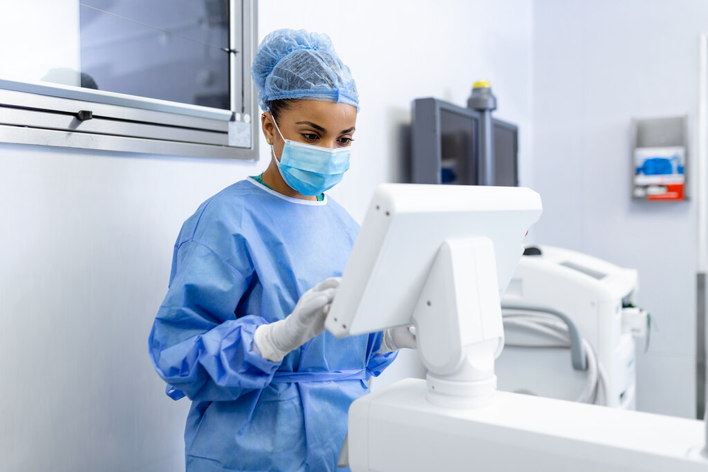 Profissional de saúde opera equipamento digital em ambiente hospitalar, destacando robótica médica e automação clínica.