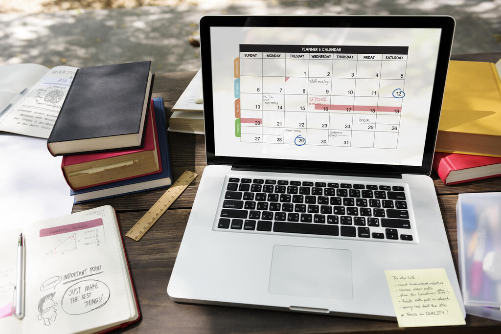 Notebook exibe calendário de estudos ao lado de livros, ilustrando como usar inteligência artificial no planejamento.