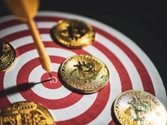 quatro moedas de bitcoin em cima de um alvo com um dardo no meio