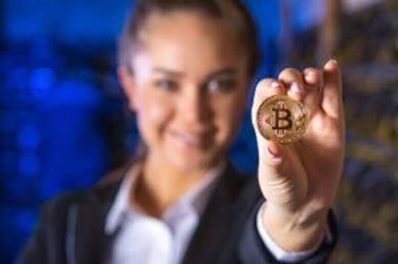 Uma mulher com uma moeda de bitcoin na mão