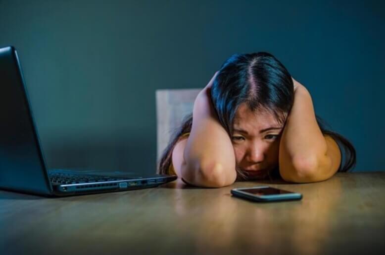 Vitimia de cyberbullying chorando na mesa