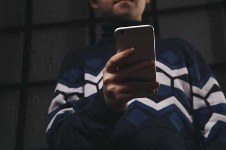 Pessoa com o celular na mão praticando cyberbullying