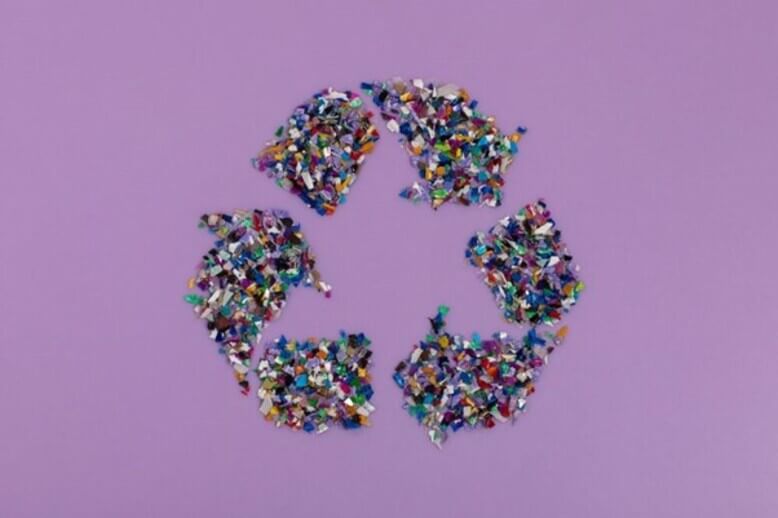 Simbolo da reciclagem feito com resíduos plásticos evidenciando a economia circular