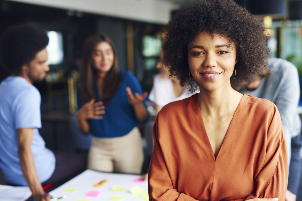 Liderança feminina em ambiente corporativo com gestora à frente de equipe durante reunião estratégica de trabalho.