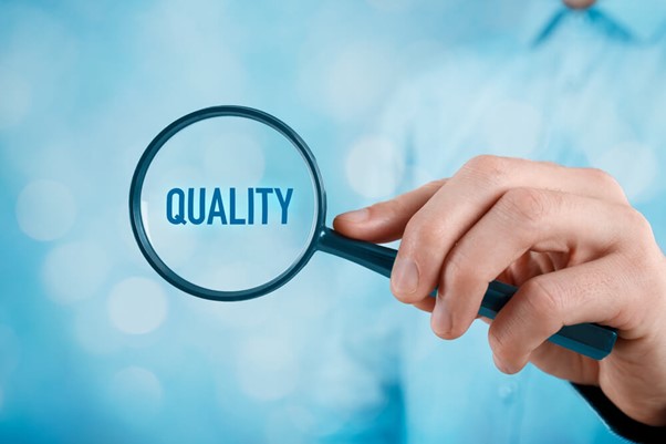 Uma pessoa segurando uma lupa evidenciando a palavra "quality" que faz referência à gestão da qualidade