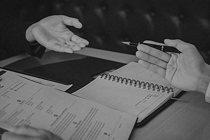 Uma mesa com anotações sobre objetivo profissional e duas mãos viradas para cima em lados opostos da mesa, como se as pessoas estivessem conversando