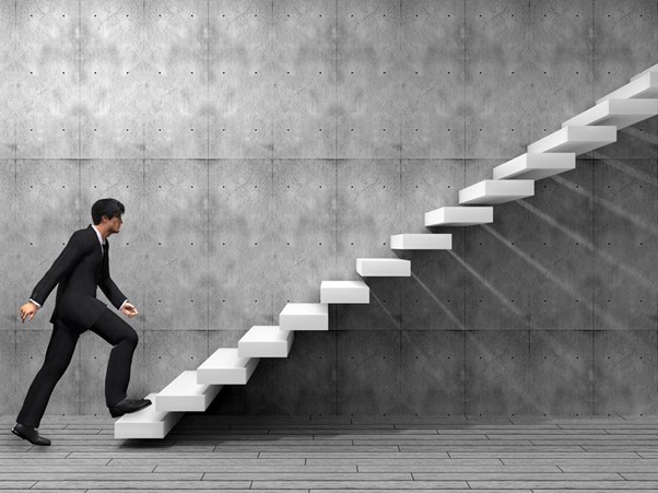 Um homem de terno social subindo as escadas atrás de seu objetivo profissional