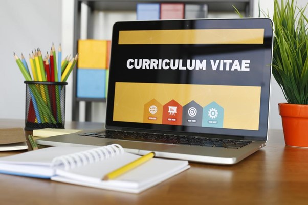 tela de computador com a frase "curriculum vitae" e na frente um caderno com anotações sobre objetivo profissional