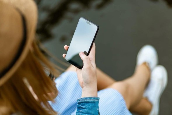 Uma moça sentada segurando um smartphone respondendo a pesquisa