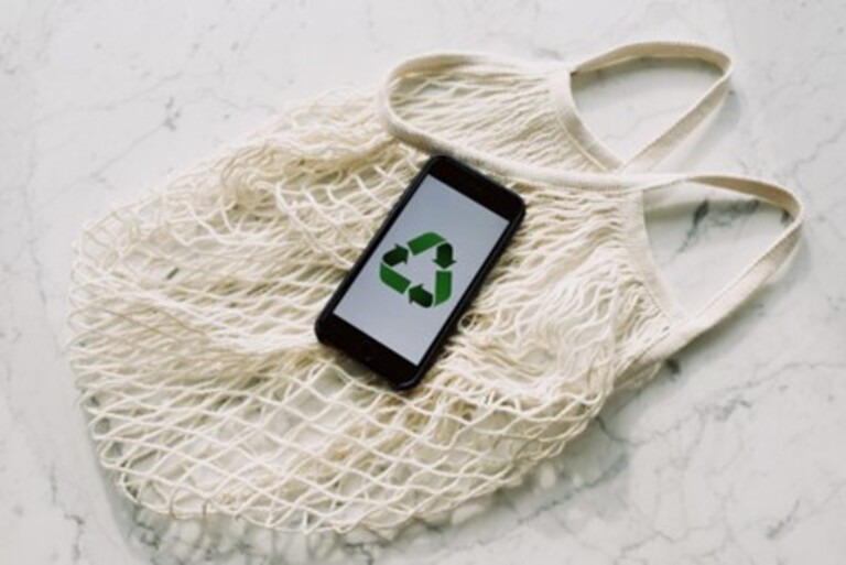 Um celular com símbolo reciclável em cima de uma sacola que também é eco friendly