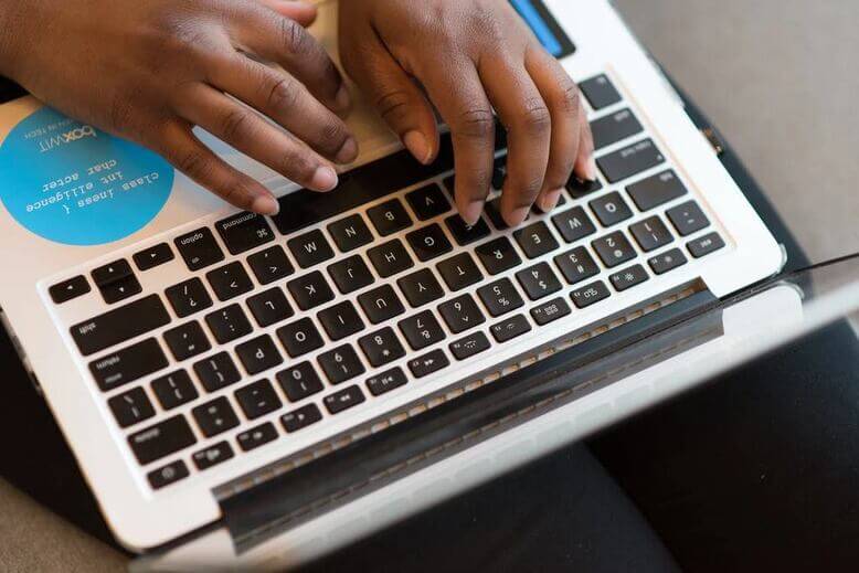 Mãos digitando em teclado de notebook sobre anywhere office