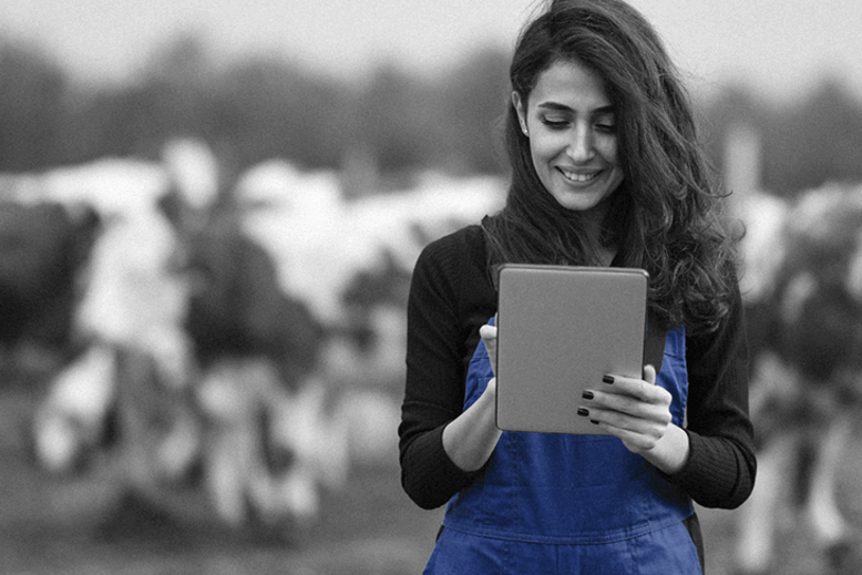 Uma mulher com tablet na mão no campo praticando a liderança feminina no agronegócio