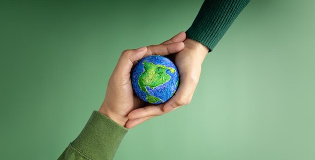 Duas mãos se encontrando com um globo terrestre no meio representando ESG