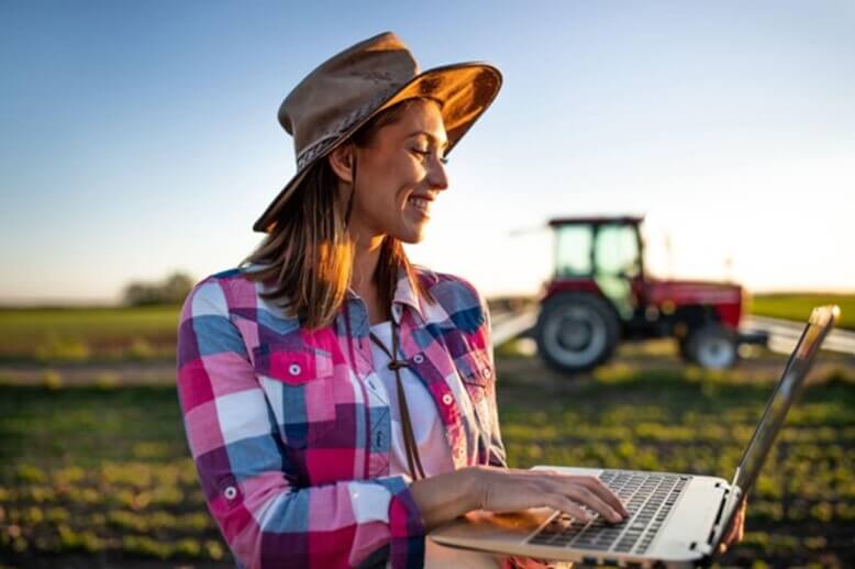 Mulher no agronegócio interagindo com notebook no meio do campo