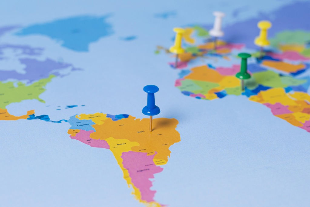 Alfinetes coloridos sobre mapa-múndi destacam a posição estratégica do Brasil nas relações internacionais.