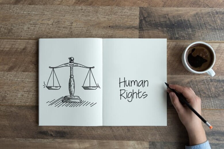 Um papel sulfite dobrado ao meio com a balança de direito de um lado e a frase "direitos humanos" em inglês do outro lado