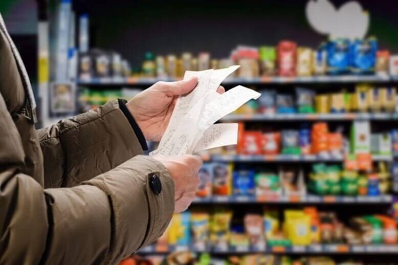 Homem acompanhando os valores impactados pela inflação na nota fiscal após compra no supermercado