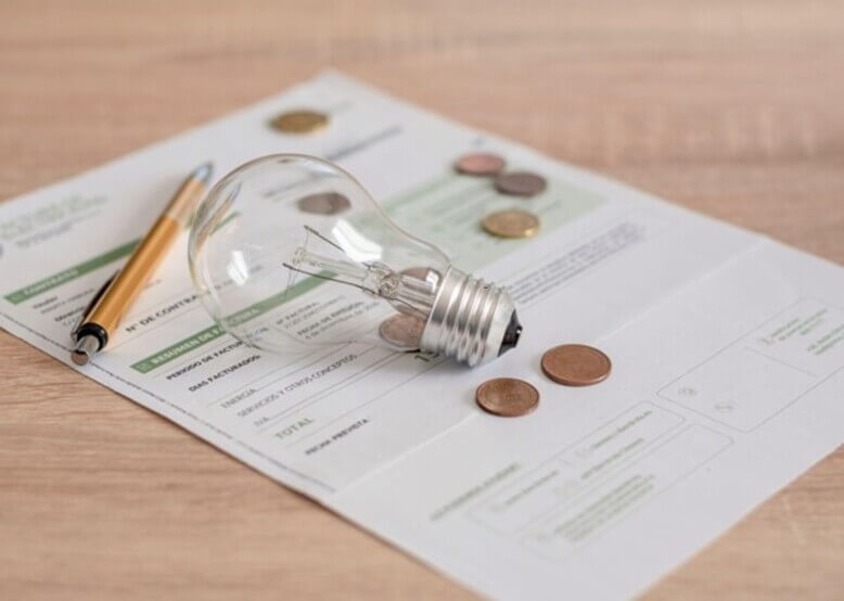 Uma lâmpada em cima de uma folha com anotações sobre a atual crise energética