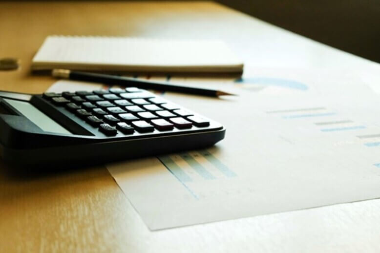 Plano de contas finalizado com papel, lápis e calculadora apoiados em cima