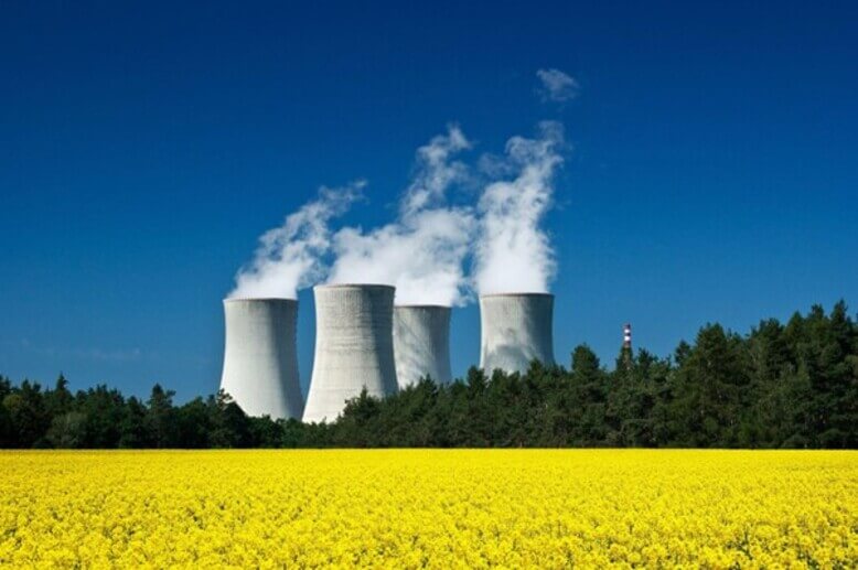 Um vasto campo verde com uma usina nuclear produzindo energia nuclear no fundo