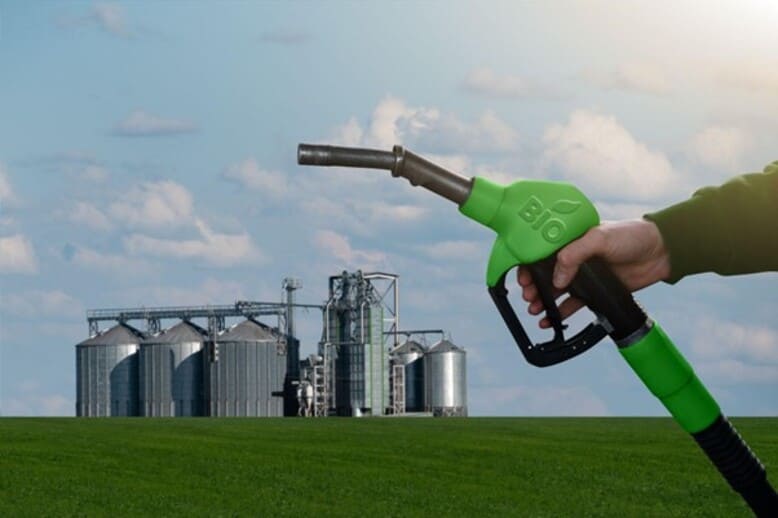 Homem segura bomba de biocombustíveis em frente a uma indústria de biocombustíveis