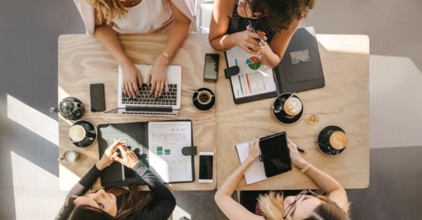 Equipe reunida em torno de uma mesa com notebooks, celulares e gráficos para analisar estratégias de neuromarketing.