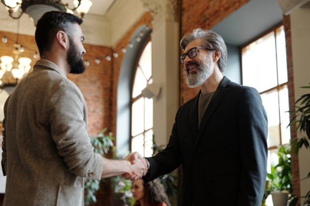 Dois homens apertando as mãos em um ambiente de negócios, simbolizando uma parceria de sucesso na gestão de compras.