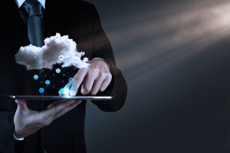 Homem de terno segurando um tablet com uma reprentação holográfica da computação em nuvem