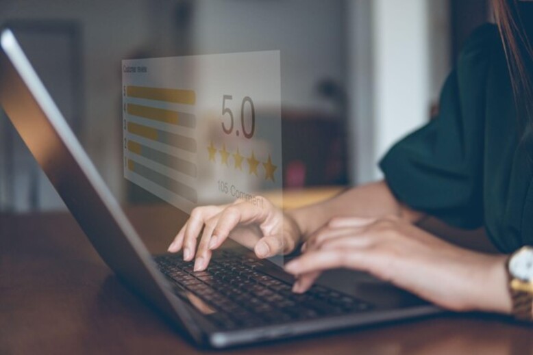 Pessoa usando um laptop com uma avaliação de 5 estrelas aparecendo na tela, simbolizando o customer success através da satisfação máxima do cliente e do feedback positivo.