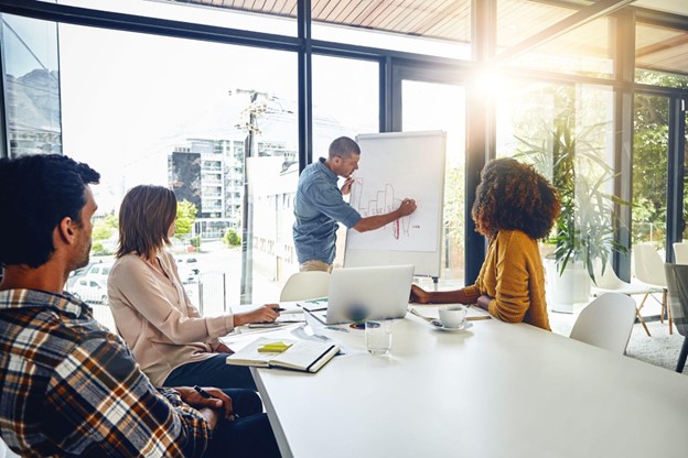 Colaboradores felizes discutindo um projeto de educação corporativa em um ambiente de trabalho colaborativo