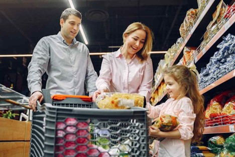 Imagem de uma lista de compras ao lado de um carrinho de supermercado cheio, ilustrando o planejamento de finanças pessoais