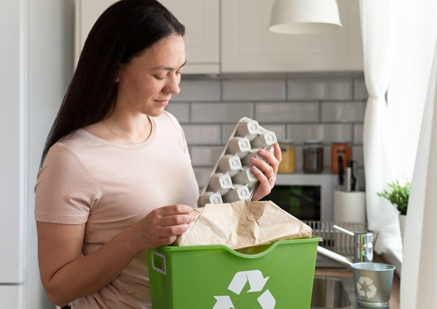 Uma mulher em um ambiente de cozinha, segurando uma embalagem de papelão para ovos. 