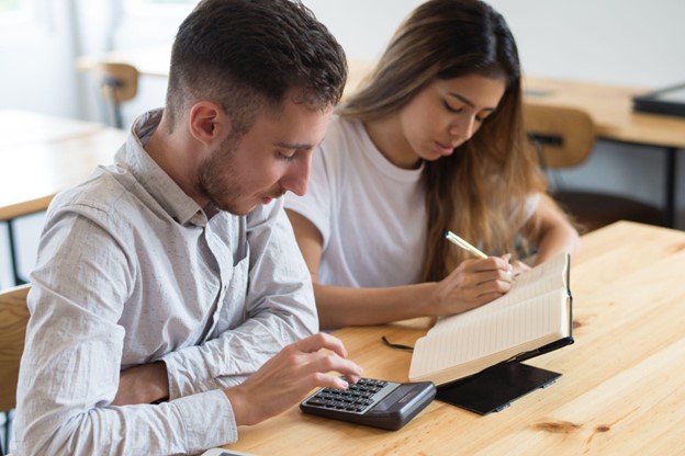 Homem e mulher fazem cálculos e anotações sobre econometria.