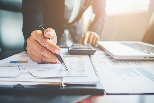 Pessoa analisando gráficos e dados financeiros em uma mesa, demonstrando como estudar economia de forma prática.