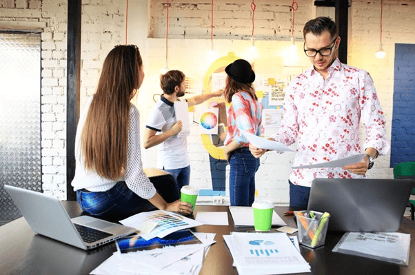 Equipe de trabalho colaborando em um escritório criativo, exemplificando a inovação dentro da economia criativa.