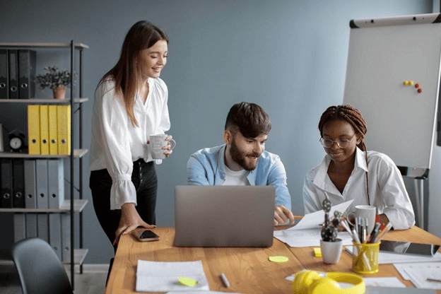 Três pessoas em um escritório colaboram em um projeto, demonstrando habilidades profissionais em um ambiente de trabalho moderno.