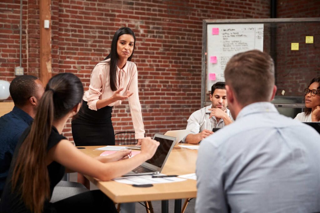 Reunião corporativa sobre sucessão empresarial, com líder orientando equipe em ambiente moderno e colaborativo.