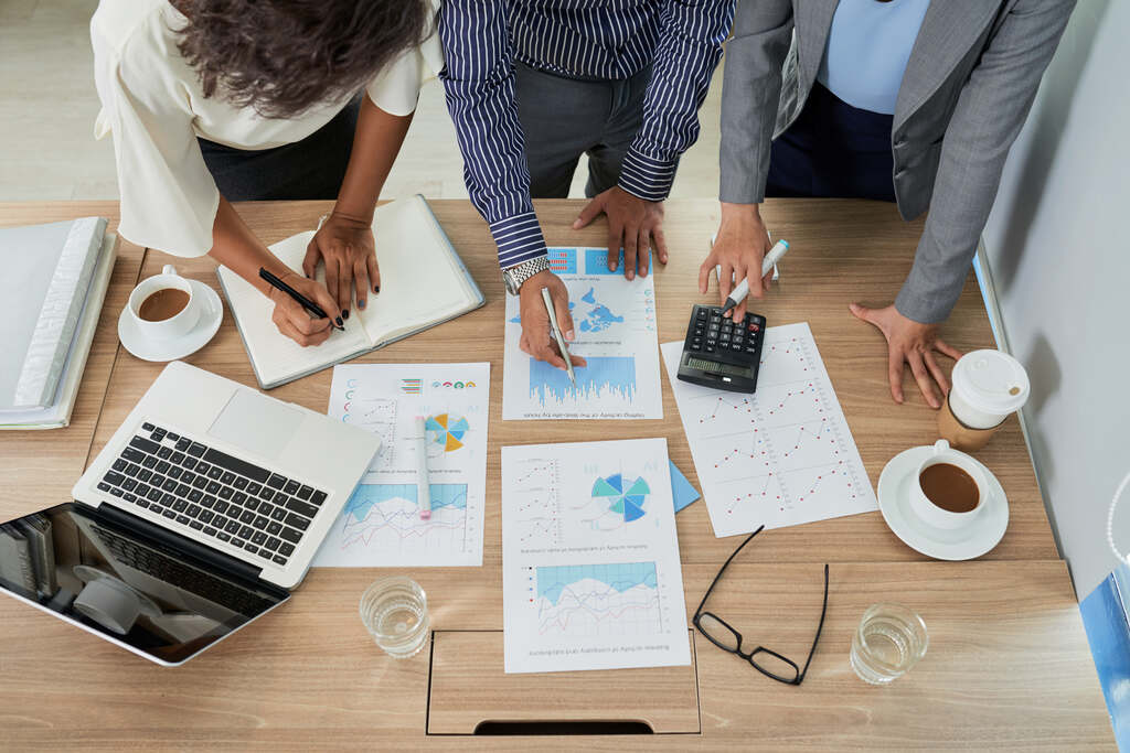 Equipe avalia relatórios financeiros e indicadores para definir estratégias de gestão de recursos.