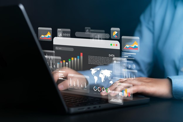 Profissional analisa dados e gráficos digitais projetados sobre notebook, representando adaptação estratégica das empresas.
fonte: adobe stock